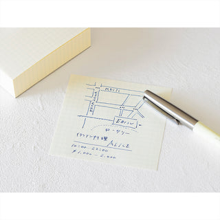 Grid memo pad sheet with blue diagram sketches and a pen on top.