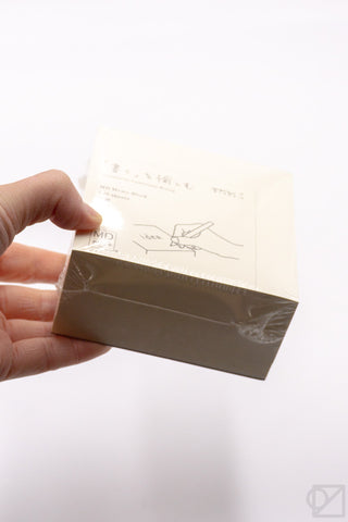 Cream memo pad block shown from side, clear top seam and dark base edge