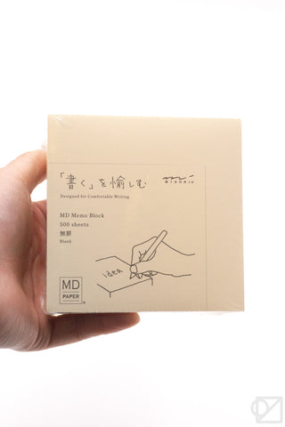 Cream memo pad block with printed cover design, held by hand