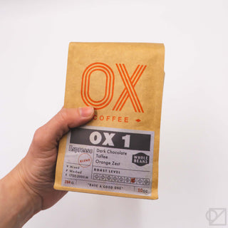 Whole bean coffee blend bag held in hand with OX 1 roast label