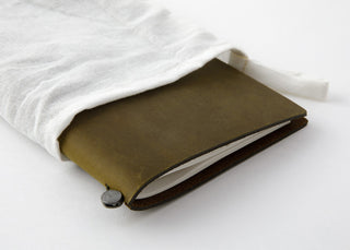 Olive notebook tucked under folded cloth with round snap closure