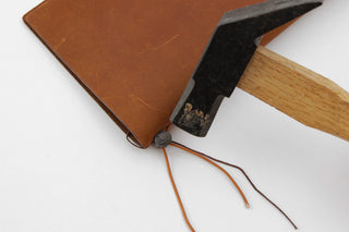 Brown notebook corner with repair tool and tied orange cords
