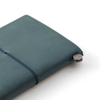 Close-up of blue leather notebook cover corner with metal button and elastic strap