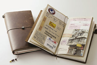 Black notebook open with travel cards and printed pages inside