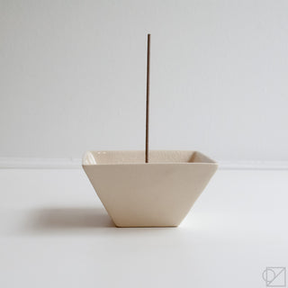 Off-white ceramic incense burner bowl with upright incense stick, side view