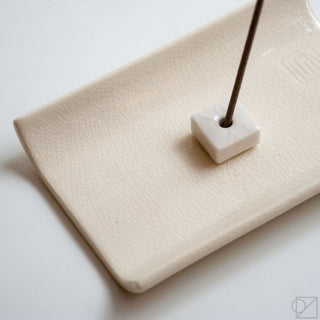 Close-up of white square incense tray with textured surface and stick holder