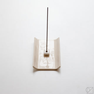 White incense burner tray with central square holder and dark incense stick