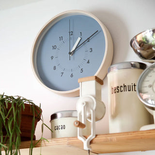 Round wall clock with blue dial and black hour and minute hands, light bezel.
