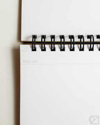 White blank notebook pages with black spiral binding rings along the edge