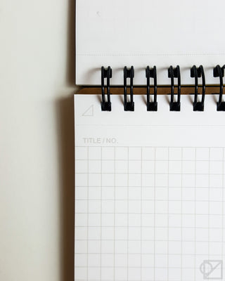 Spiral notebook binding with black rings and white grid pages