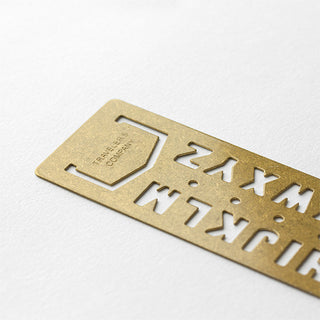Brass alphabet template bookmark with cutout letter shapes and central guide