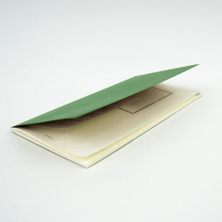 Closed notebook with green cover flap raised; cream pages peek out