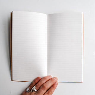 Open lined notebook with white ruled pages and brown spine