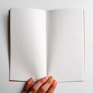 Blank notebook open to white pages with tan page edges and visible binding