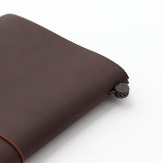 Brown leather notebook corner with gray button and elastic strap loop.