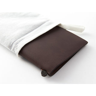 Brown leather traveler's notebook wrapped in a white cloth pouch with button clasp.