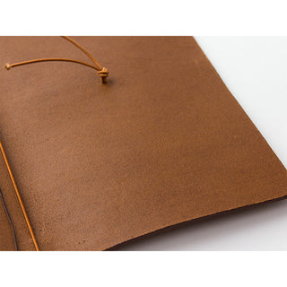 Camel-brown leather notebook close-up with tied cord closure on cover