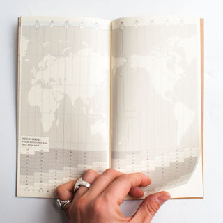 Open monthly planner notebook with world map theme and printed calendar grid