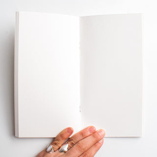 Open sketch paper notebook with blank pages, hand at the bottom edge