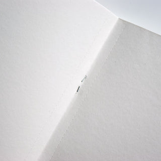 Sketch paper notebook spine seam with stitched binding and small metal eyelet
