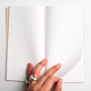 Lightweight paper notebook, open to blank white pages with beige cover.
