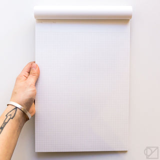 Grid notepad with white pages and light gray graph lines, white backing roll