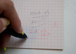 OHTO MULTI-B 2+1 matte black pen with fine tip, shown writing on lined paper
