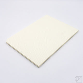 Closed cream graph paper pad on a flat surface, grid pattern visible on top page.