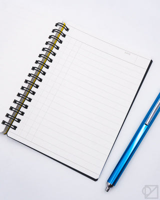 A6 daily notebook opened flat with grid lines and blue ballpoint pen