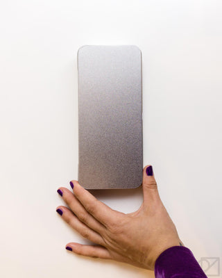 Flat stainless steel pen case with textured silver finish, held by a hand