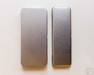 Metal pen case pair: one closed and one open, textured silver-gray finish