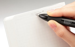 STÁLOGY 018-Grid Editor’s Notebook with grid pages and a pen writing at the top