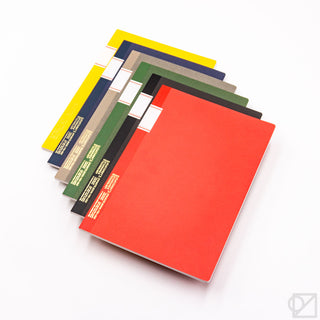 STÁLOGY 016 B5 notebooks stacked in red, yellow, blue, gray, black, and green
