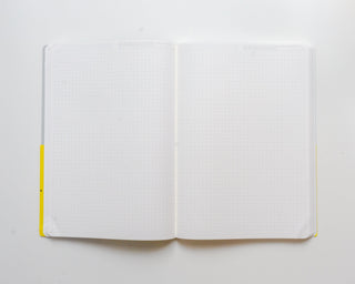 STÁLOGY grid editor's notebook open to blank grid pages with yellow page tabs