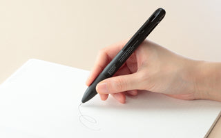 Black 4Functions pen in hand, fine tip drawing a circle on paper
