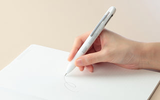 White 4Functions pen in hand, fine tip drawing an oval on paper