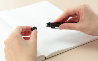 Black 4Functions pen with end piece being adjusted between hands