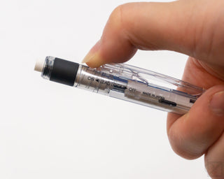 Hand adjusting the ON/LEAD LOCK OFF switch on a clear blue mechanical pencil