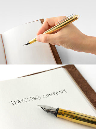 Brass fountain pen with fine nib being used to write in an open notebook