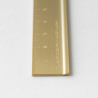 Brass metric ruler corner view with engraved scale and 'TRC' mark