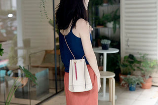 White crossbody pouch with a red and black portable ballpoint pen clipped inside