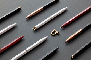 Multiple ballpoint pens with white barrels and gold clips arranged on dark background