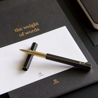 Black ystudio rollerball pen with gold tip and clip on paper